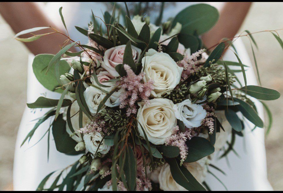 Bride holding a cascading bouquet of white and pink roses with greenery.
