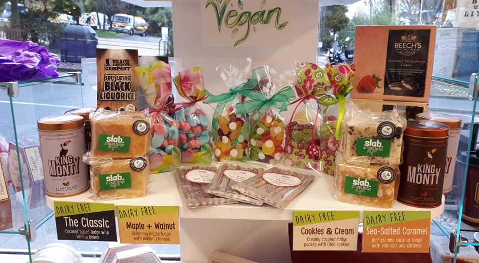 Vegan treats display in a shop window, featuring brownies, cookies, and other packaged sweets.