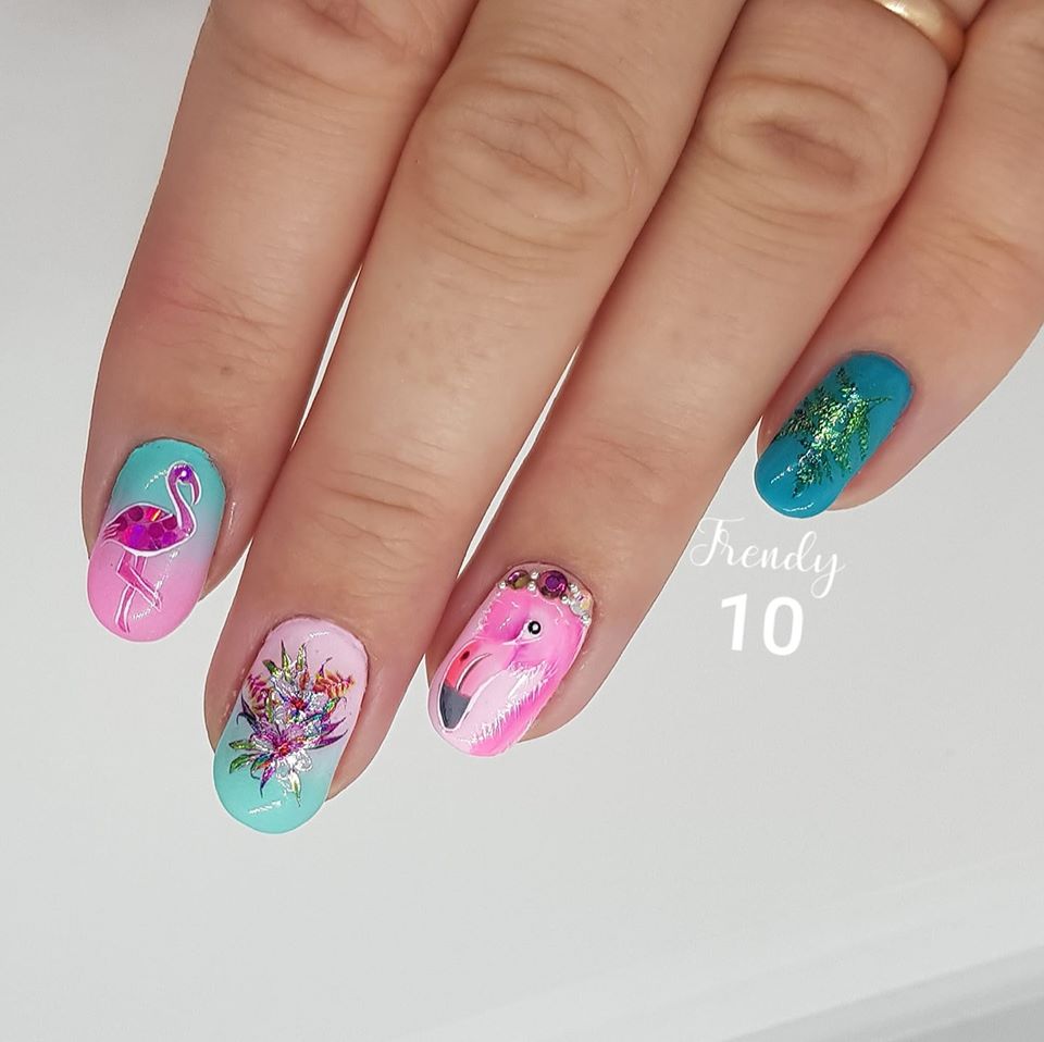 Close-up of hand with decorated nails; pink and teal flamingo designs.