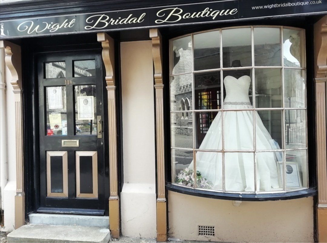 Wight Bridal Boutique storefront with a wedding dress in the window. Black door and light pink exterior.