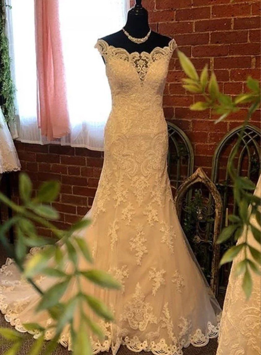 Wedding dress on a mannequin in a shop with a brick wall backdrop.
