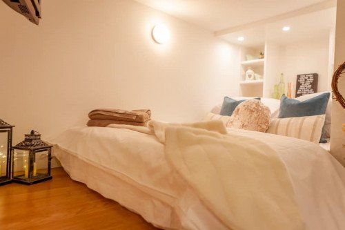 Cozy bedroom with a bed, white bedding, pillows, and decorative lanterns.