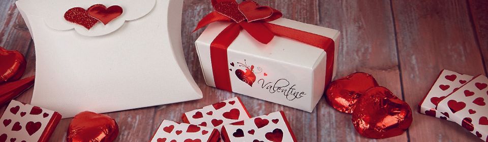 White gifts with red hearts and ribbons on a wooden surface, Valentine's Day.