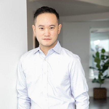 A man in a white shirt is leaning against a wall.