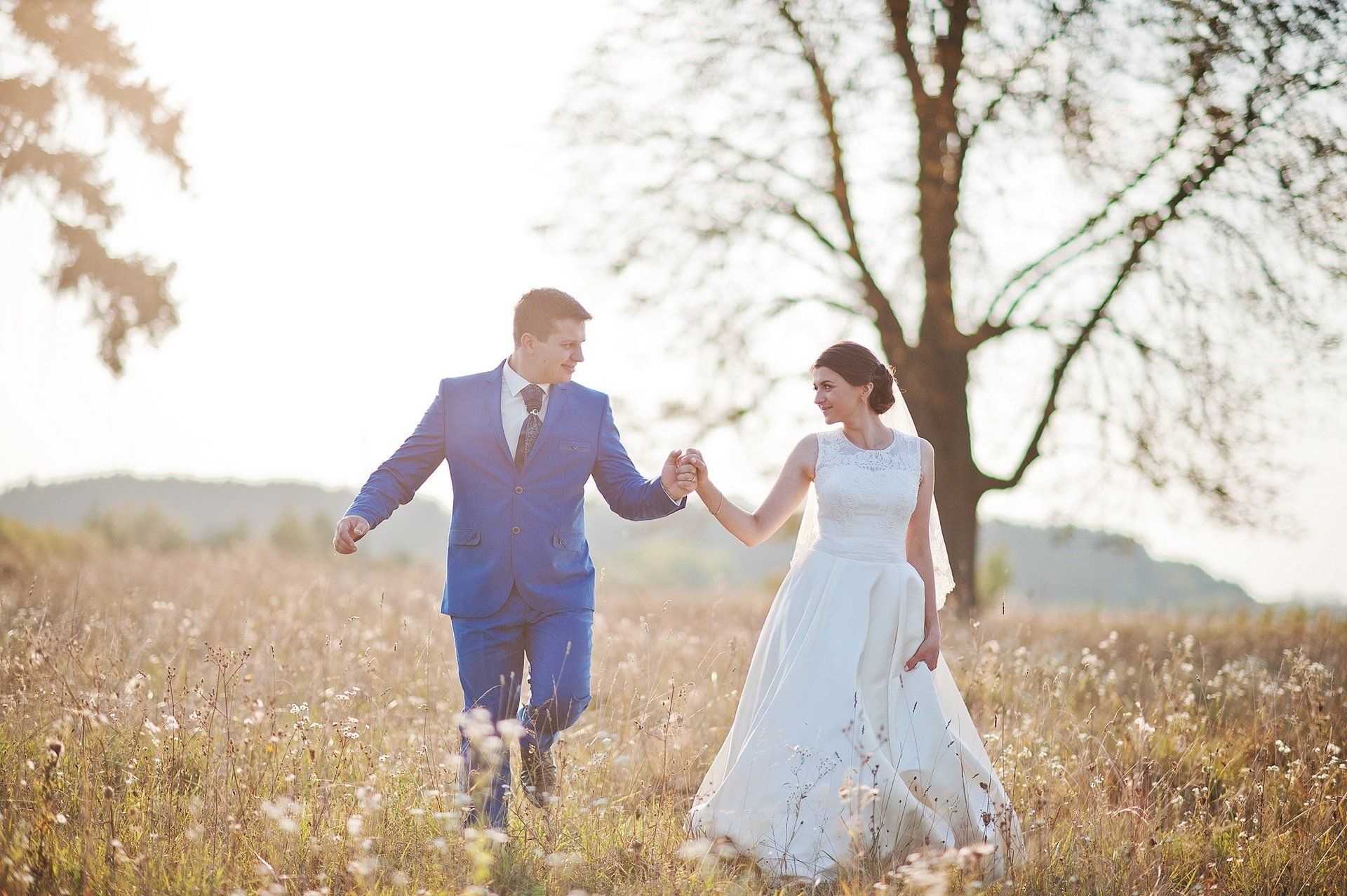 Bride and groom walking through field