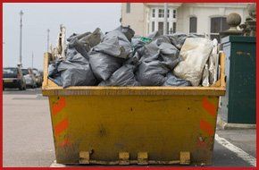 yellow skip full of grey waste bags on a street