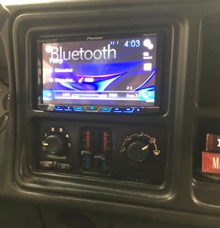 Car dashboard with a touchscreen stereo displaying Bluetooth and climate controls below