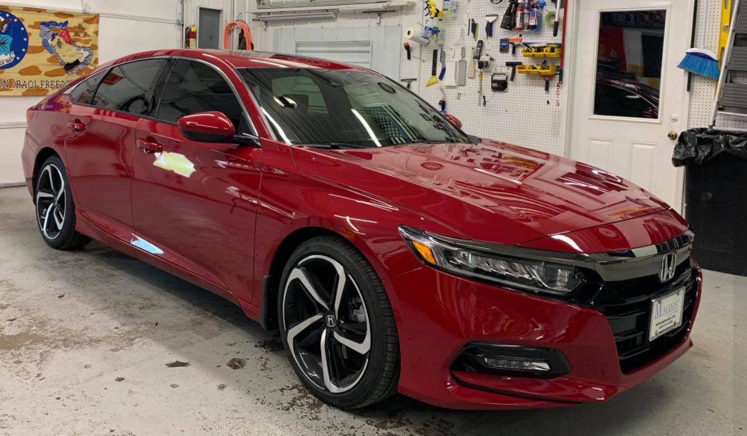 Red sedan in a garage, shown from the front-left side.