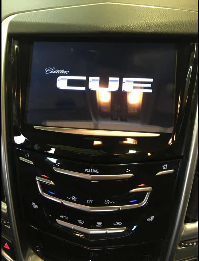 Car dashboard center console with touchscreen displaying “CUTE” and climate control buttons below