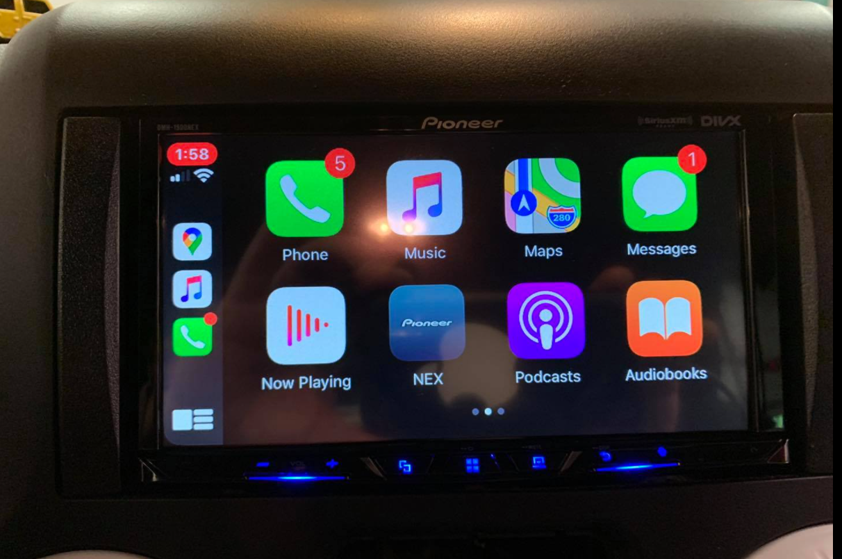 Car dashboard showing a Pioneer touchscreen with Apple CarPlay app icons and notification badges.