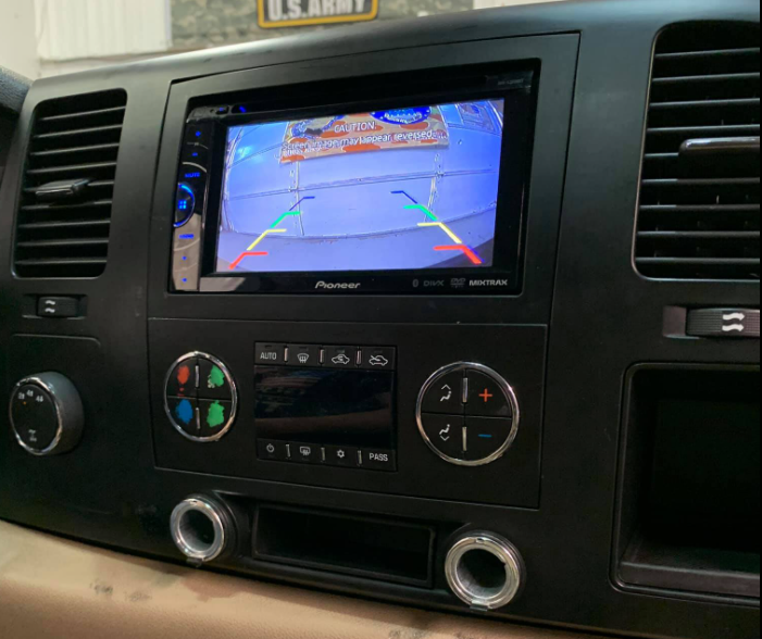 Car dashboard with a Pioneer infotainment screen showing rearview camera guidelines and climate controls below.