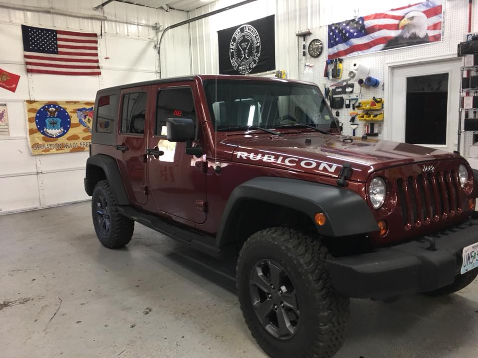 Maroon Jeep Rubicon in a garage with American flags and wall decor
