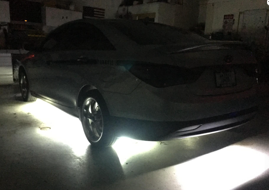 Dark sedan parked at night, underglow lights illuminating the ground underneath.