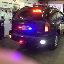 Dark blue SUV with flashing red and blue lights at an indoor auto show