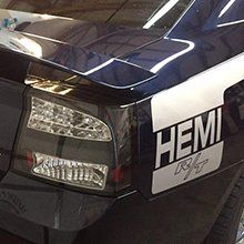 Close-up of a dark car’s rear taillight and trunk badge with a large “HEMI” decal.