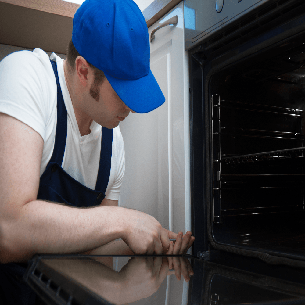 Appliance Repair Company — A Man With Blue Cap Repairing The Oven in Westerly, RI Appliance Repair Company — A Man With Blue Cap Repairing The Oven in Westerly, RI
