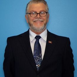 A man in a suit and tie is smiling for the camera