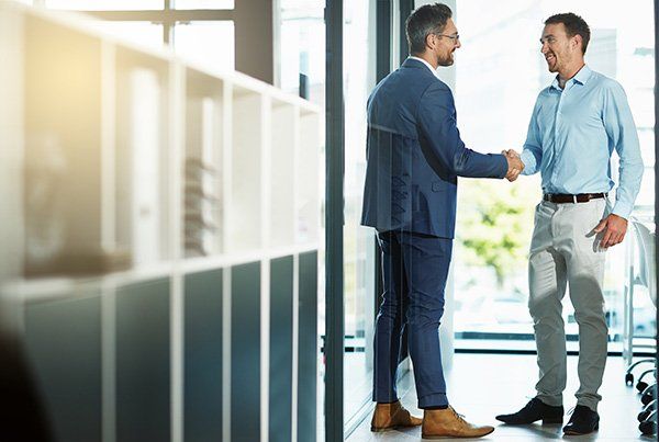 Two businessmen shake hands in an office.
