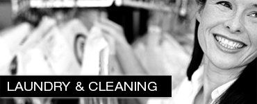 Woman smiles next to blurred clothes on hangers,