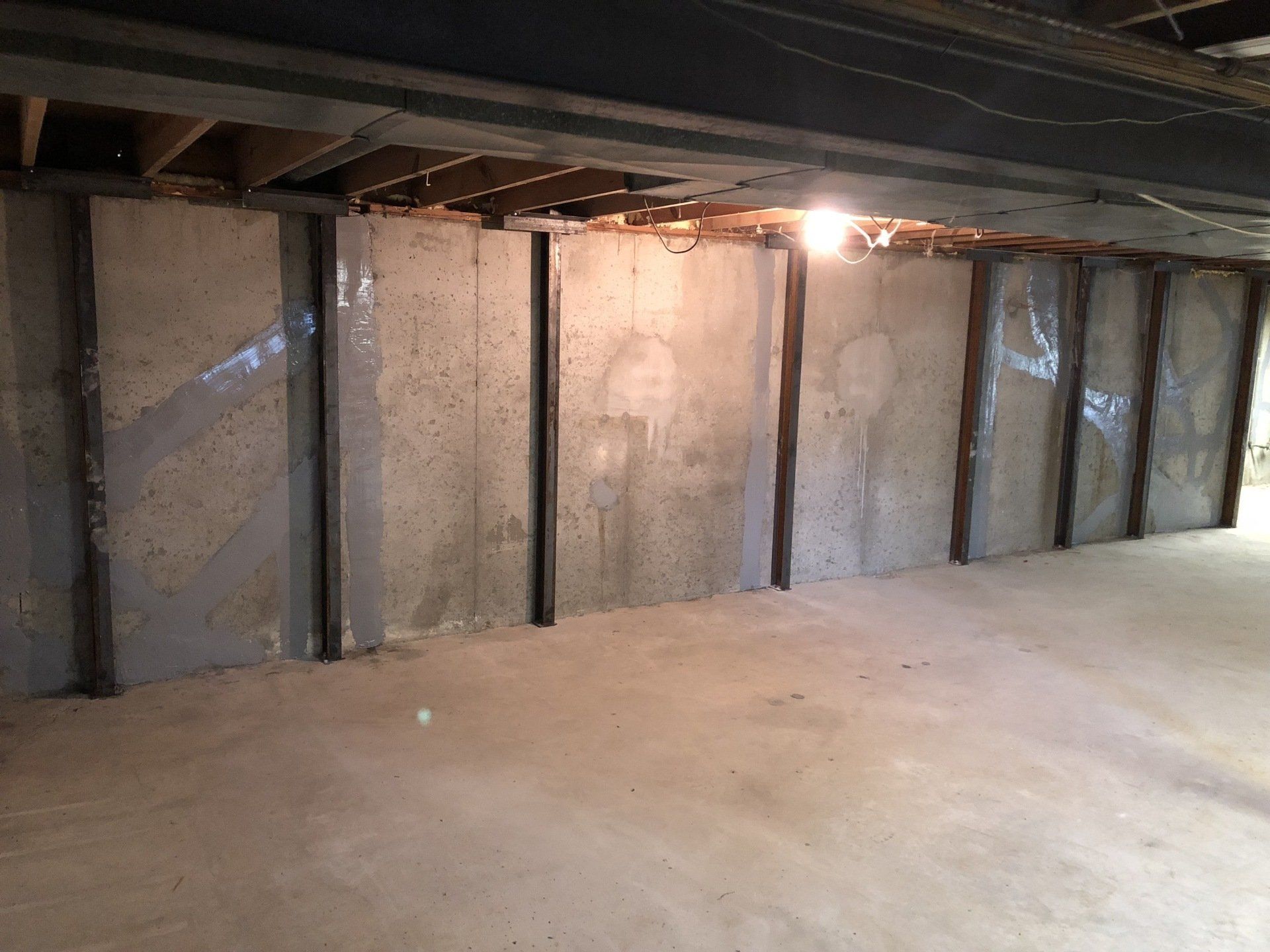 Concrete basement wall reinforced with steel beams.