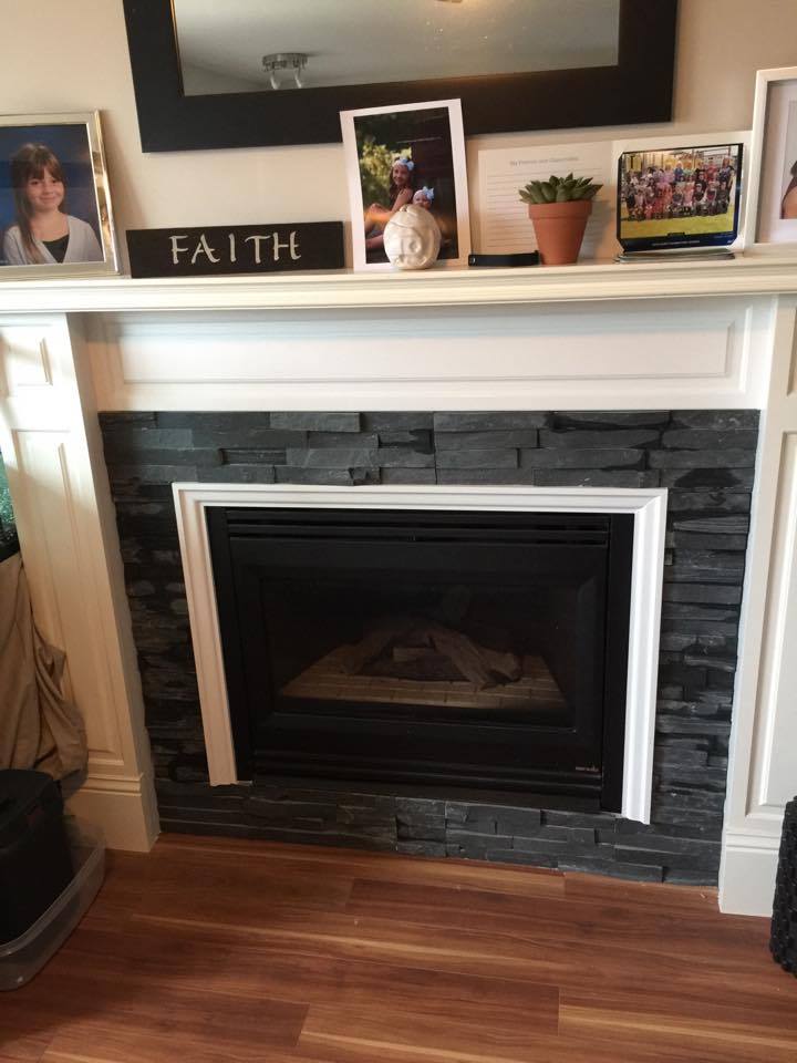 Fireplace with black stone facade, white trim, and a mantel with decorations.