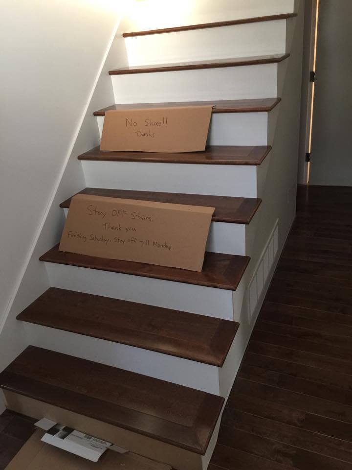 Wooden staircase with cardboard signs on two steps, possibly for renovation.