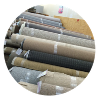 Rolls of carpet in various neutral colors, stacked in a shop.