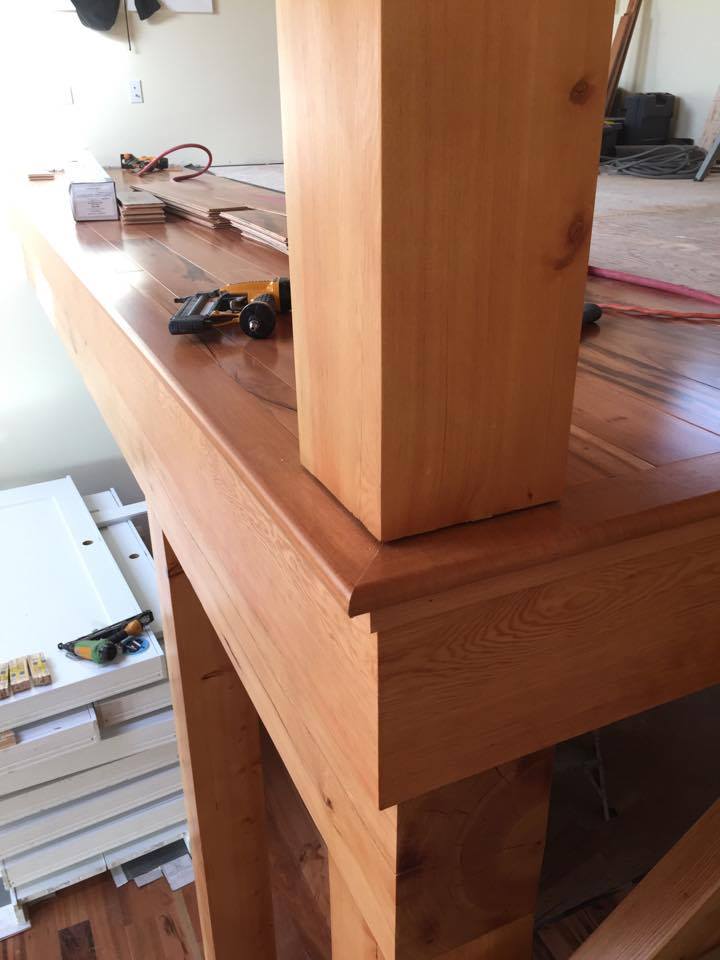 Wooden fireplace mantel with a square column on top. The room is under construction.