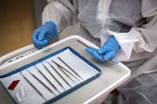 A dentist prepares for an aerosol generating procedure wearing full PPE.