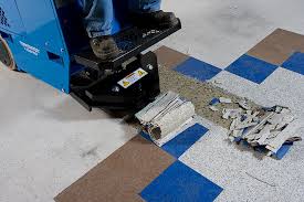 Blue floor-cleaning machine with a squeegee and debris on a tiled floor