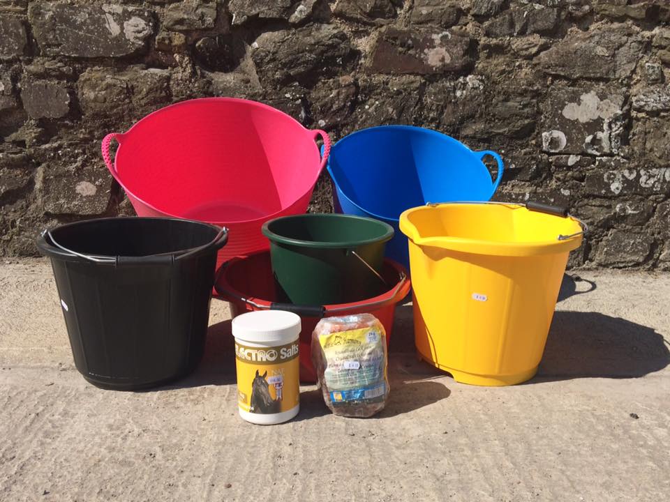 buckets and a container of active salt sit in front of a stone wall