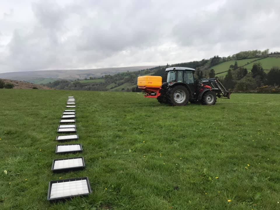 a tractor is spraying a grassy field with a yellow tank