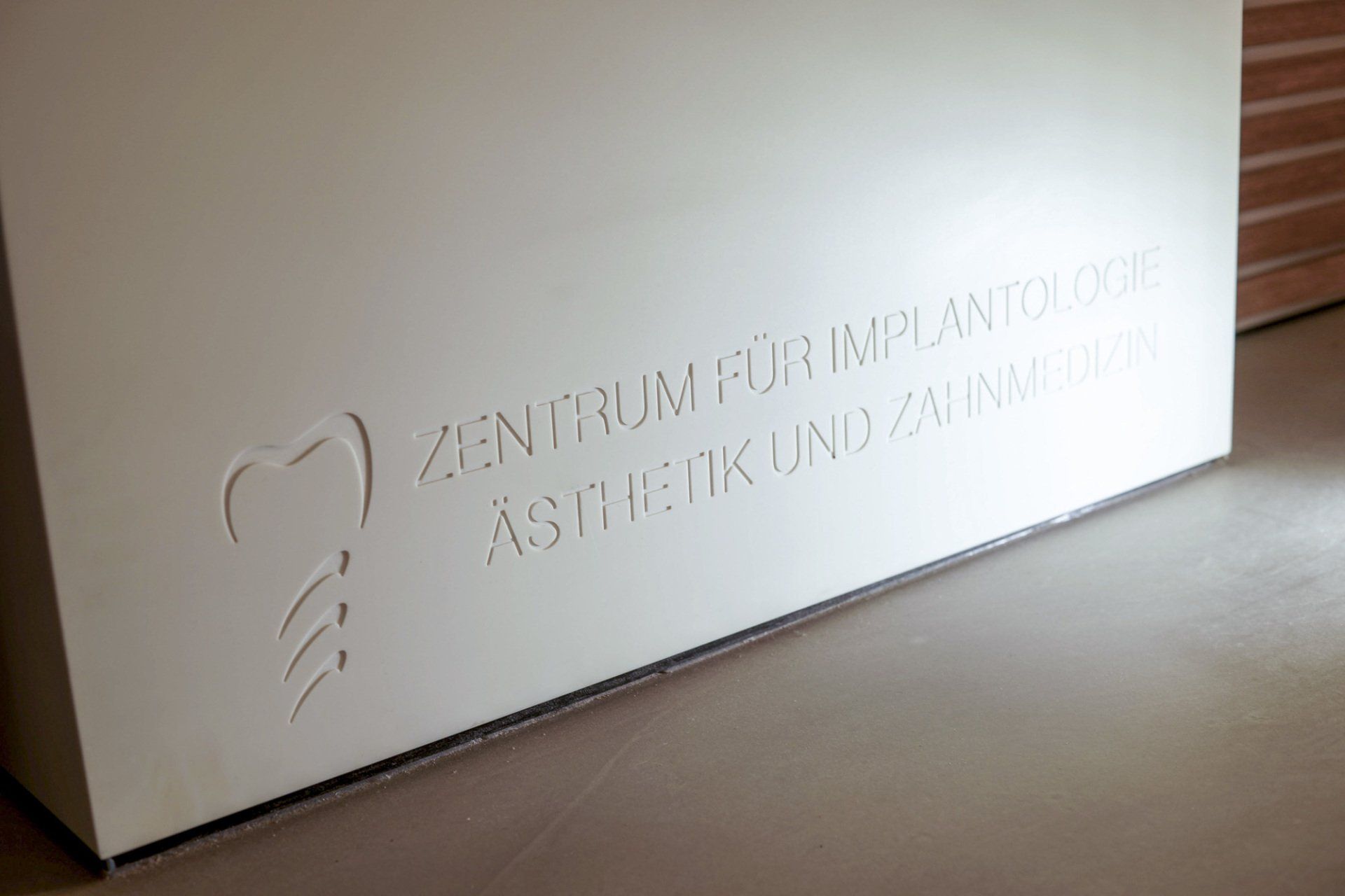 Ein weißer Kasten mit der Aufschrift „Zentrum für Implantologie Ästhetik und Zahnmedizin“