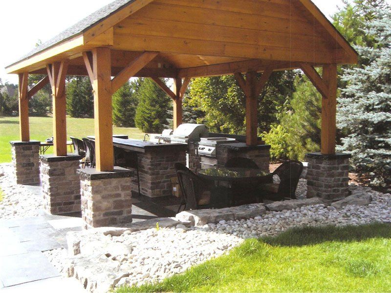 A wooden gazebo with a grill underneath it