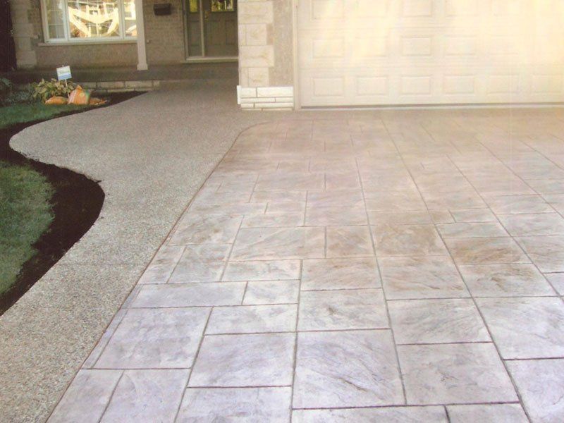 A concrete driveway with a walkway leading to a house