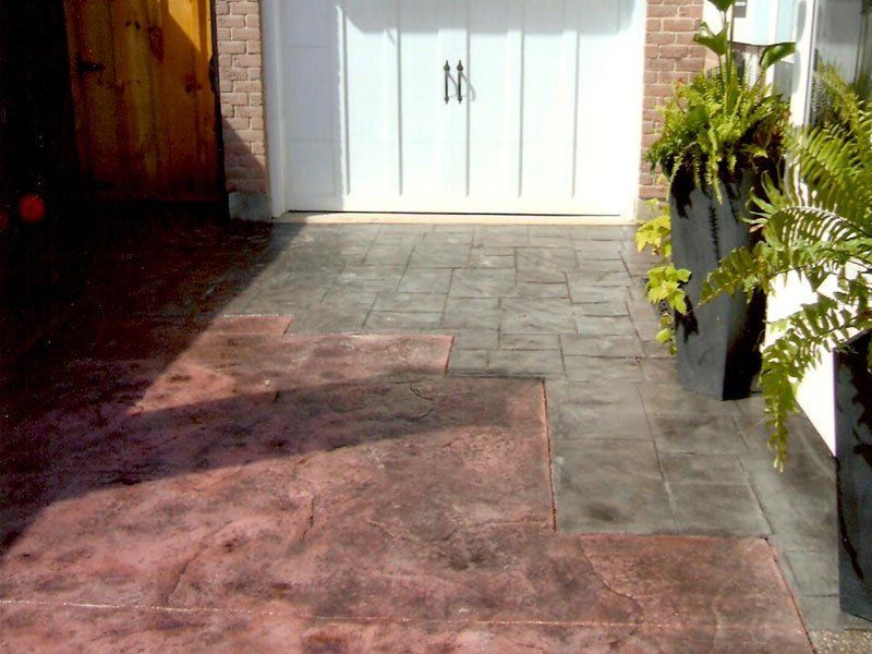 A driveway with a planter in front of a garage door.