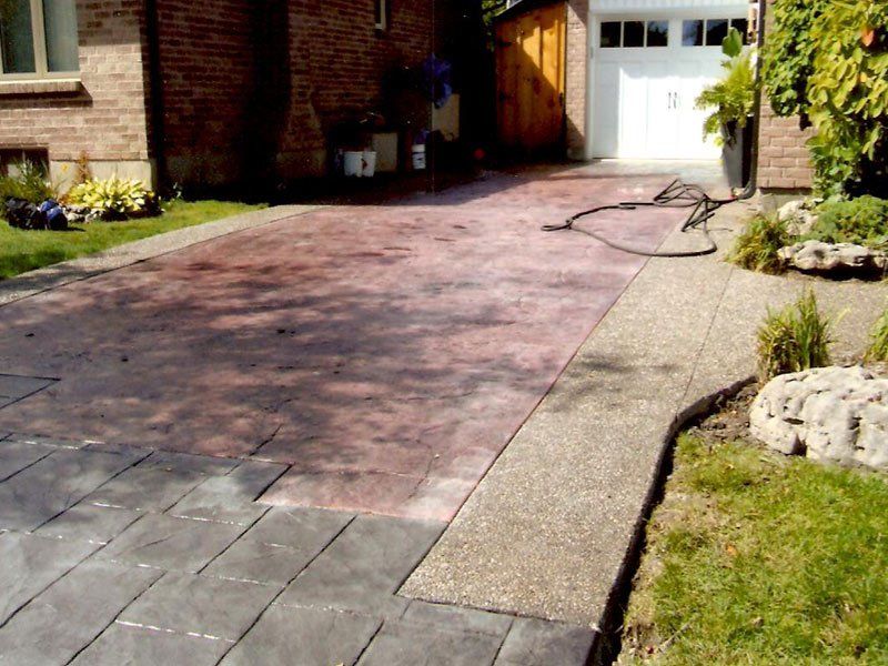 A driveway in front of a brick house with a white garage door