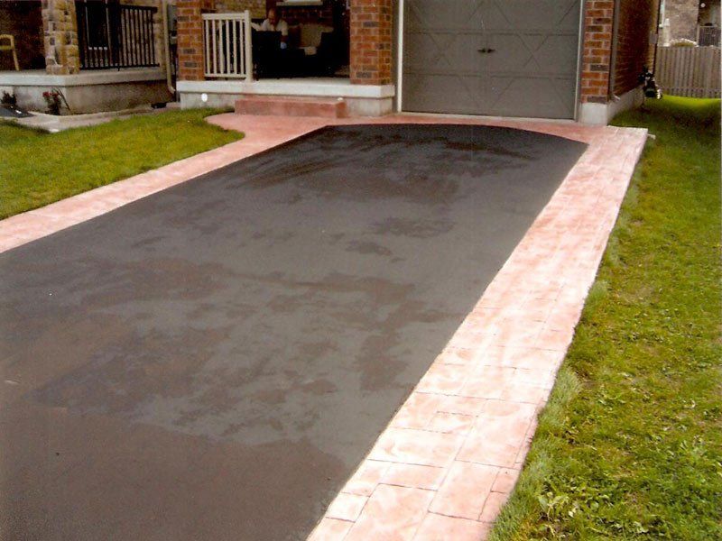 A driveway with a brick walkway leading to a garage