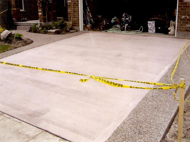 A concrete driveway with a yellow caution tape around it