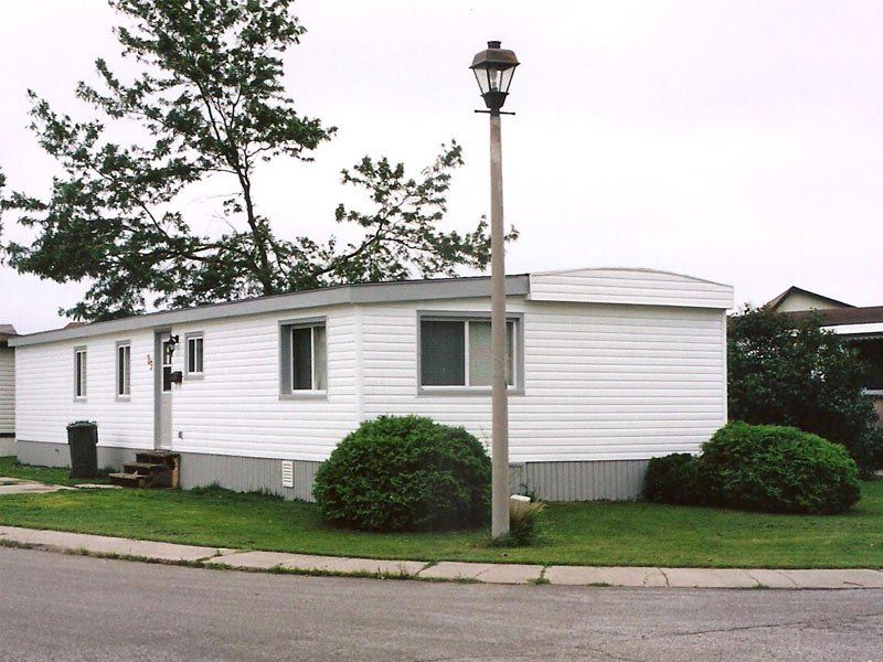 A white mobile home with a street light in front of it