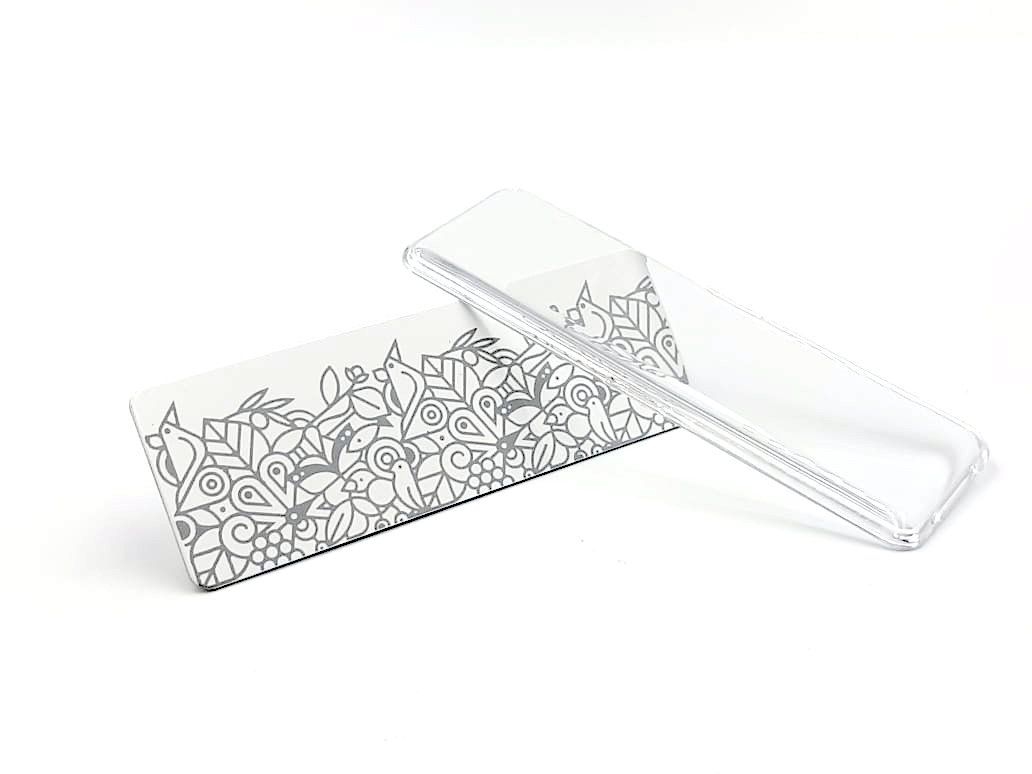 Caja de cosméticos rectangular blanca con estampado floral negro y tapa transparente sobre fondo blanco.