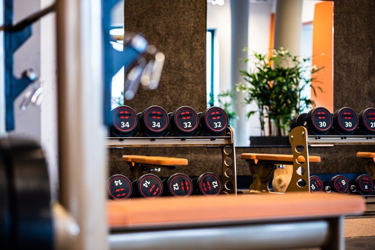 Een sportschool met veel halters en banken.