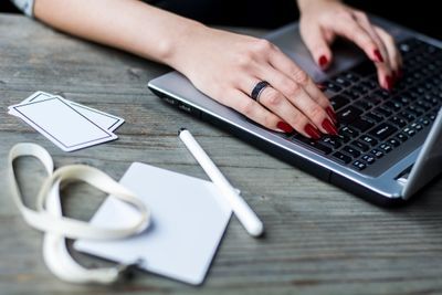 A woman with red nails is typing on a laptop