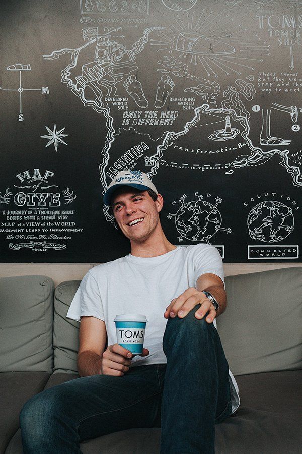 A man is sitting on a couch holding a cup of coffee.