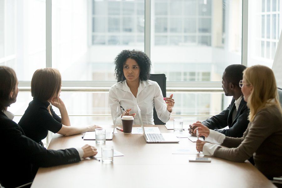 A group of people are sitting around a conference table having a meeting.