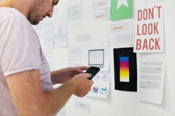A man is using a cell phone in front of a sign that says do n't look back