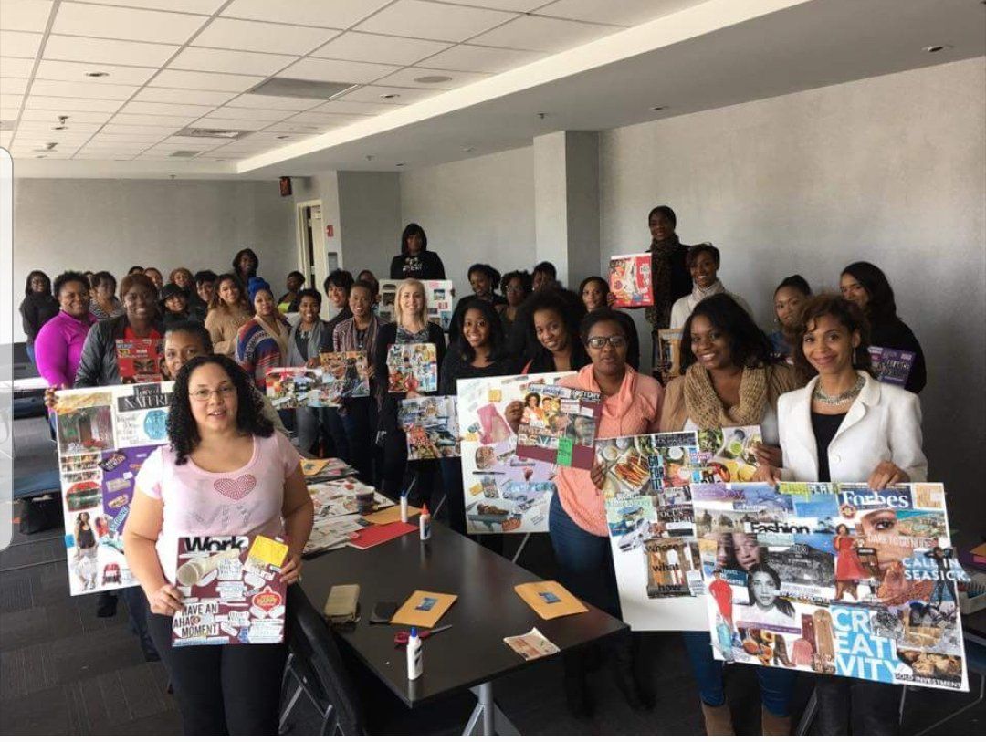 A group of people are standing around a table holding paintings.