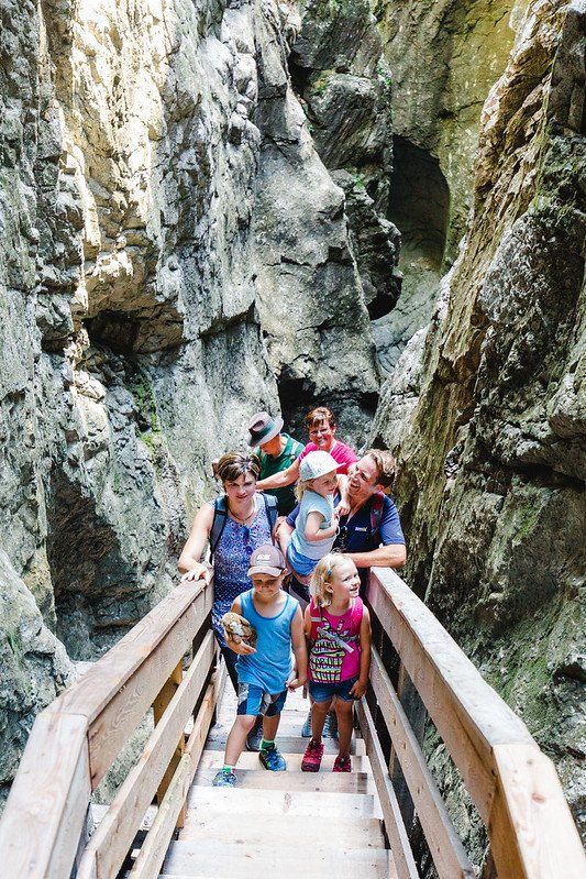 Eine Gruppe Wanderer überquert eine Holzbrücke durch eine enge Felsenschlucht.
