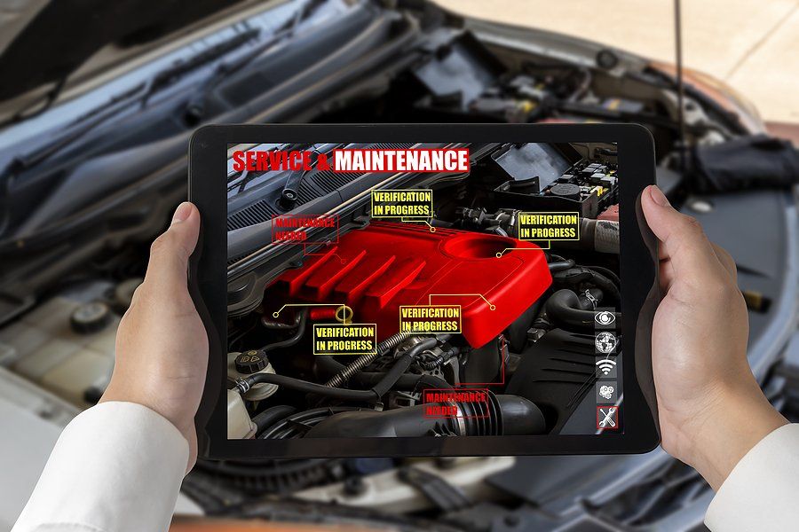 Hands holding tablet displaying augmented reality car engine maintenance guide.