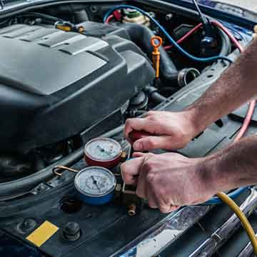 Hands of a mechanic using gauges to service a car engine.